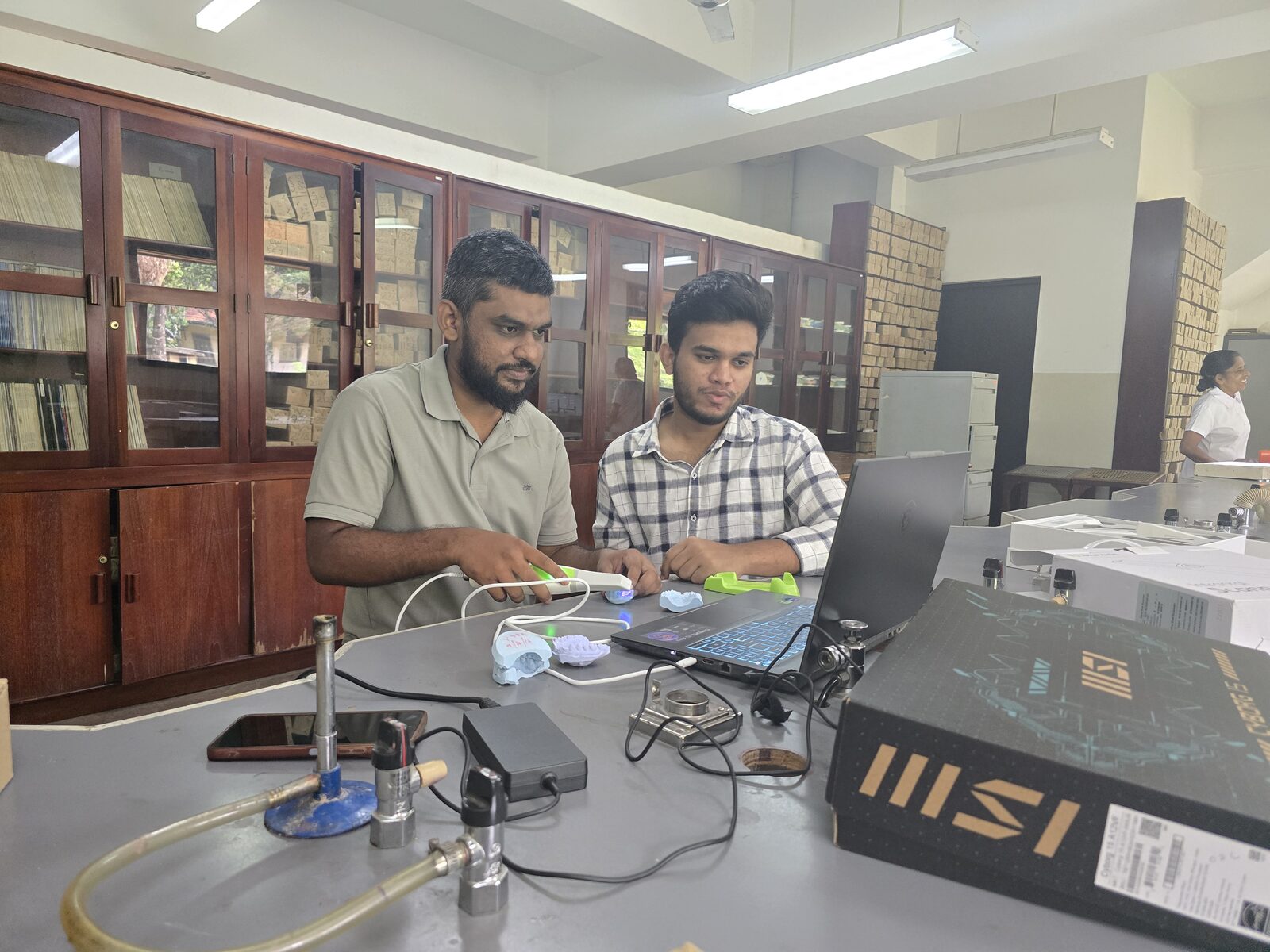 Two team members operating the handheld scanner and laptop together in the lab