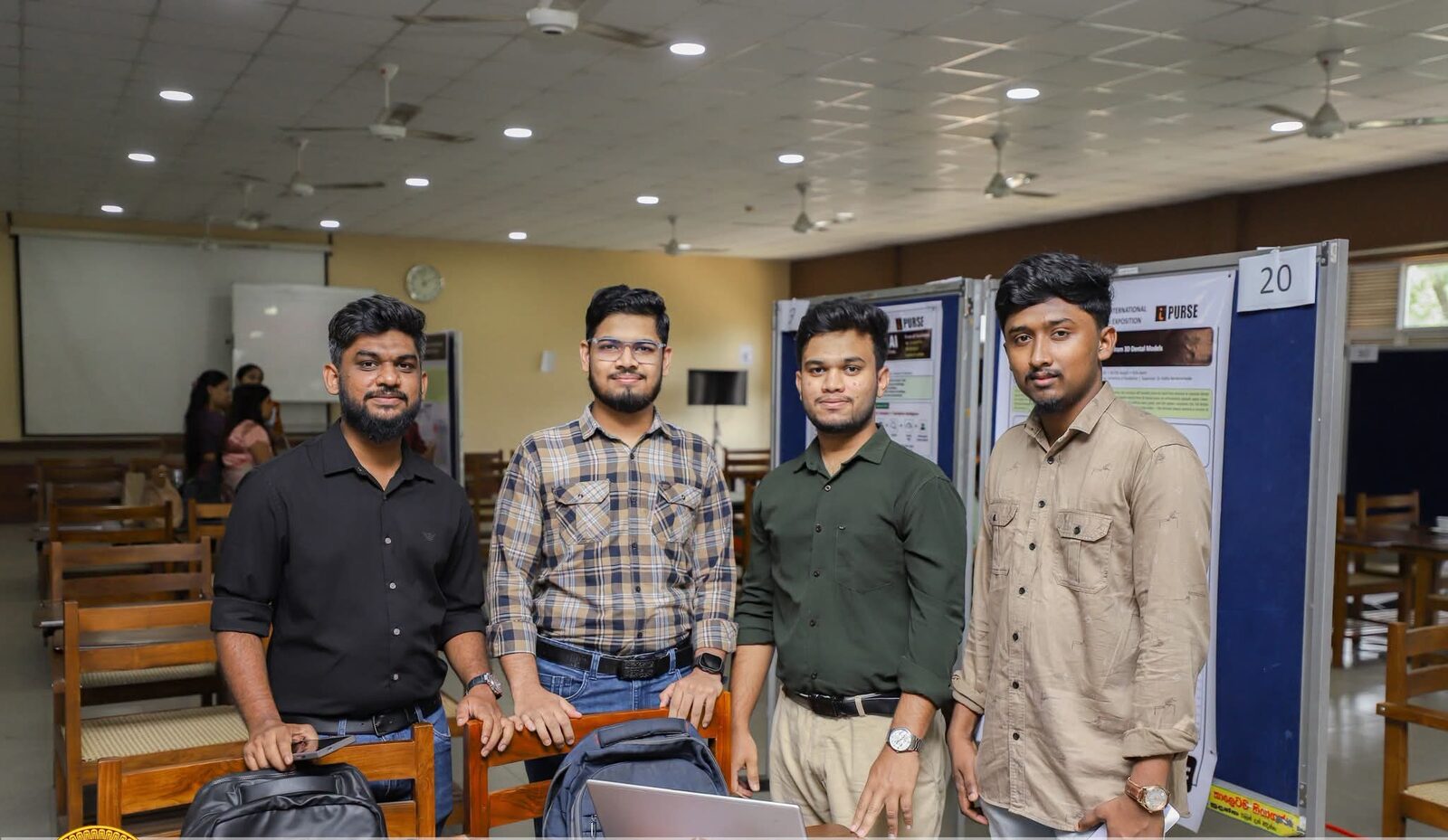 The four-member team standing beside their project poster at a research exposition